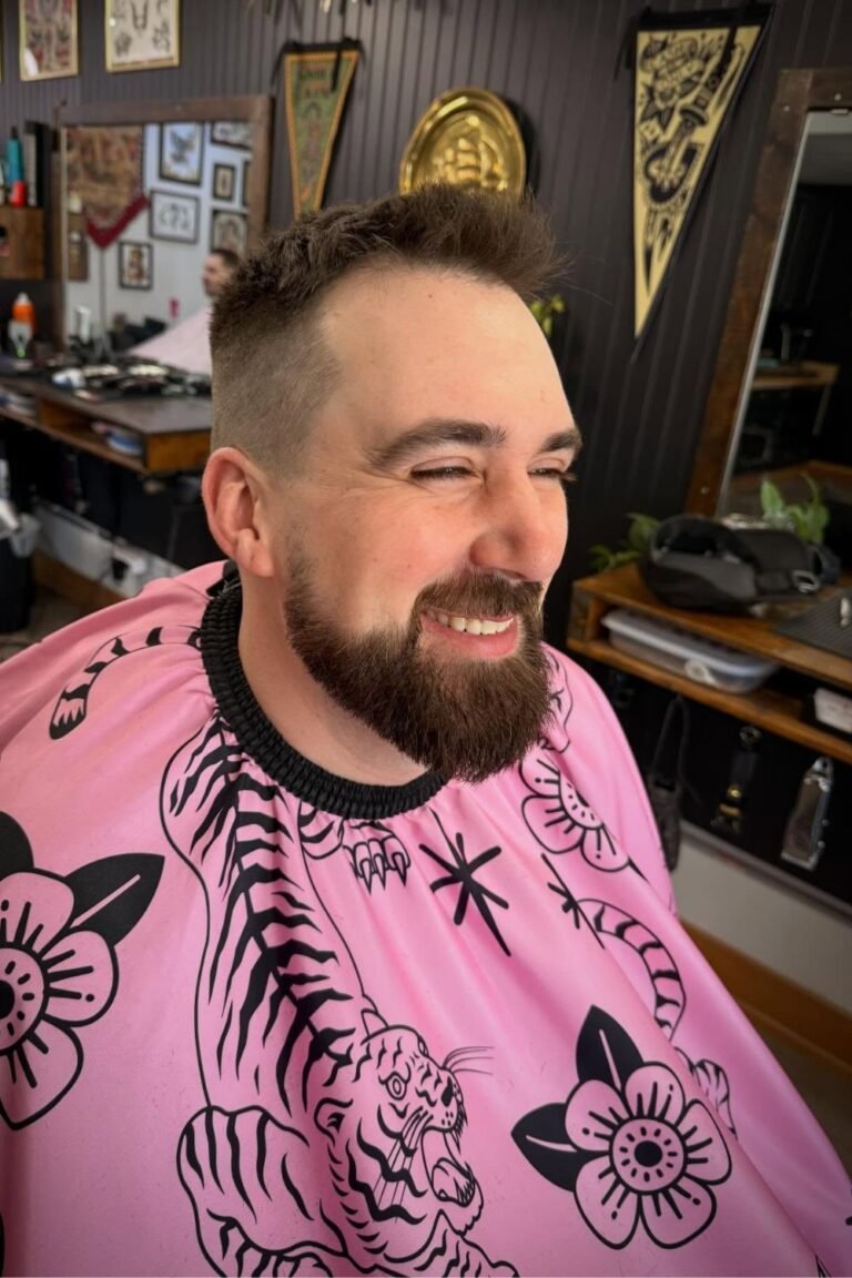 Brass Anchors Barbershop with a man smiling in the barber chair with a p;ink smock